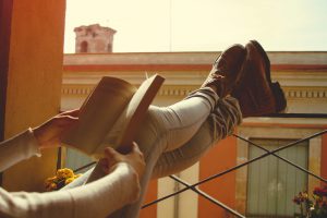 Women legs reading book on balcony , relaxing